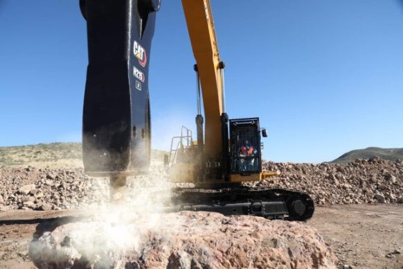 Cat hydraulic hammer attachment on an excavator breaking up rocks